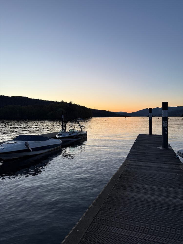 Sunset over Lake Windermere with boats moored at the Wake District jetty